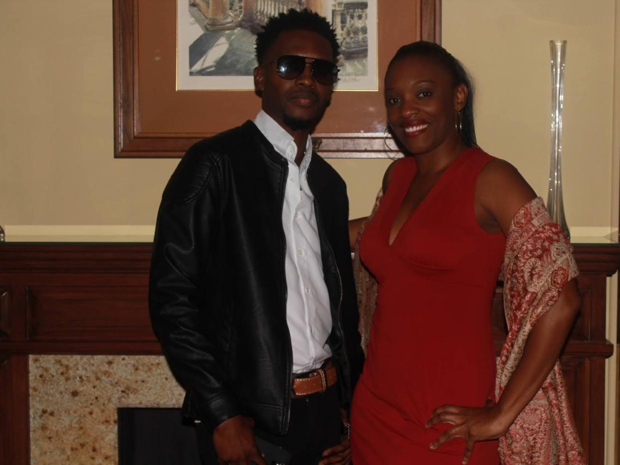 The author, Taayoo Murray, wearing a red dress and her brother, wearing a white shirt and black jacket, smiling for the camera