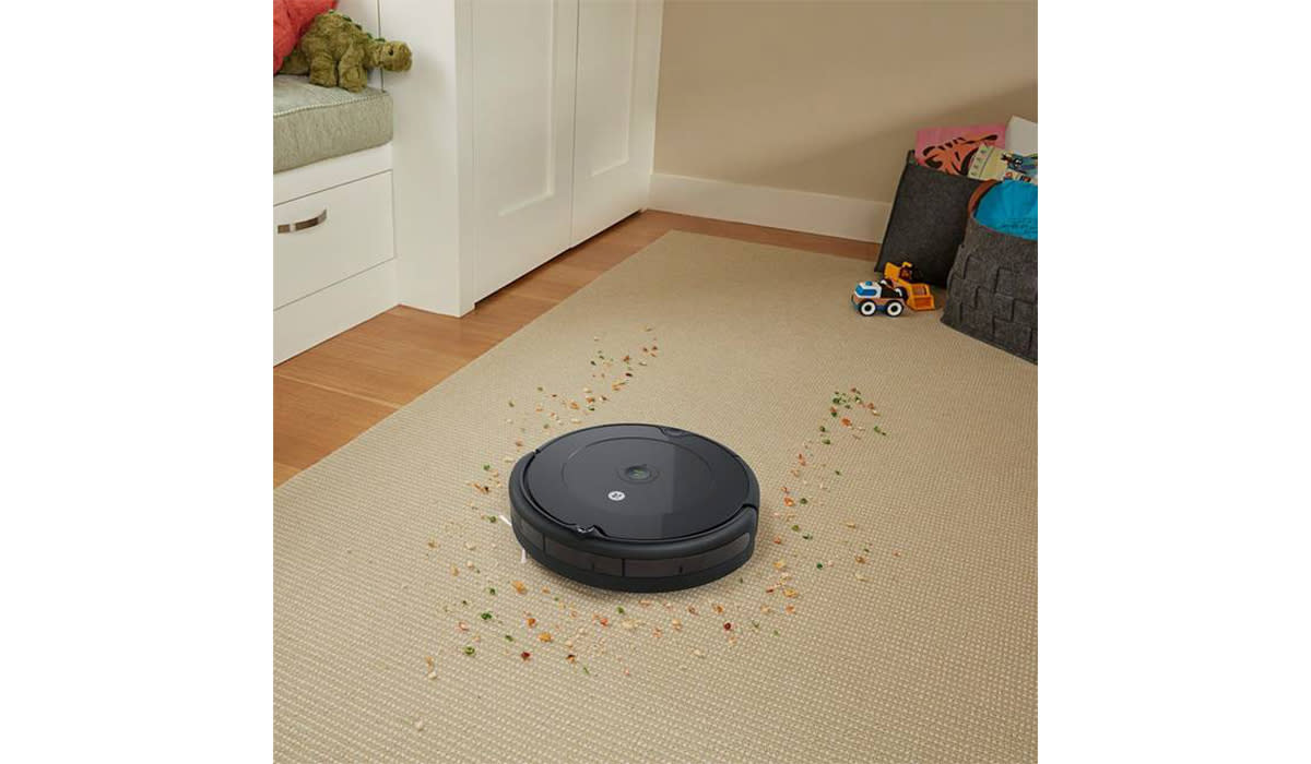 iRobot Roomba 694 on carpet cleaning spilled cereal near a basket of toys.