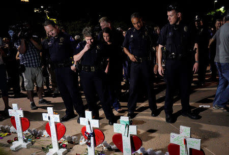 Members of the Aurora police department look over crosses for those killed in the Aurora theater shooting, at a vigil on the 5-year anniversary of the tragedy in Aurora, Colorado, U.S. July 20, 2017. REUTERS/Rick Wilking