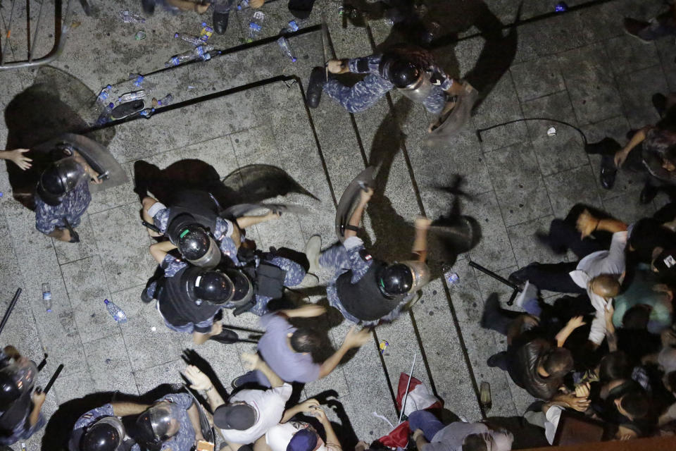 Anti-government protesters clash with riot policemen on a road leading to the government house in downtown Beirut, Lebanon,, Friday, Oct. 18, 2019. Lebanon erupted in protests Thursday over the government's plans to impose new taxes amid a severe economic crisis, taking their anger on politicians they accuse of widespread corruption and decades of mismanagement. (AP Photo/Hassan Ammar)