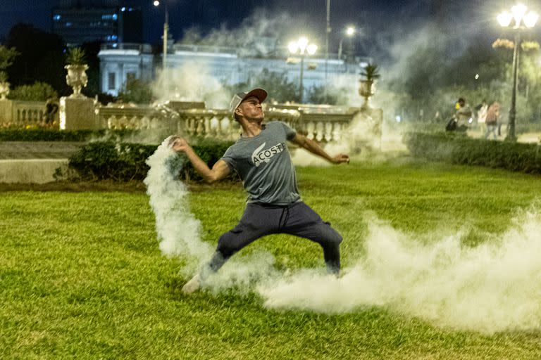 Un manifestante se apresta a arrojar una granada lacrimógena encendida