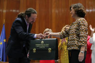 Podemos (United We Can) leader Pablo Iglesias, left, receives his ministerial briefcase from First Deputy Prime Minister Carmen Calvo in Madrid, Spain, Monday, Jan. 13, 2020. Iglesias will be one of four deputy prime ministers and in charge of social rights and sustainable development after a total of 22 ministers took their oaths in Spain's center to far left-wing coalition administration, a first in a country once dominated by two main parties taking turns in power. (AP Photo/Manu Fernandez)