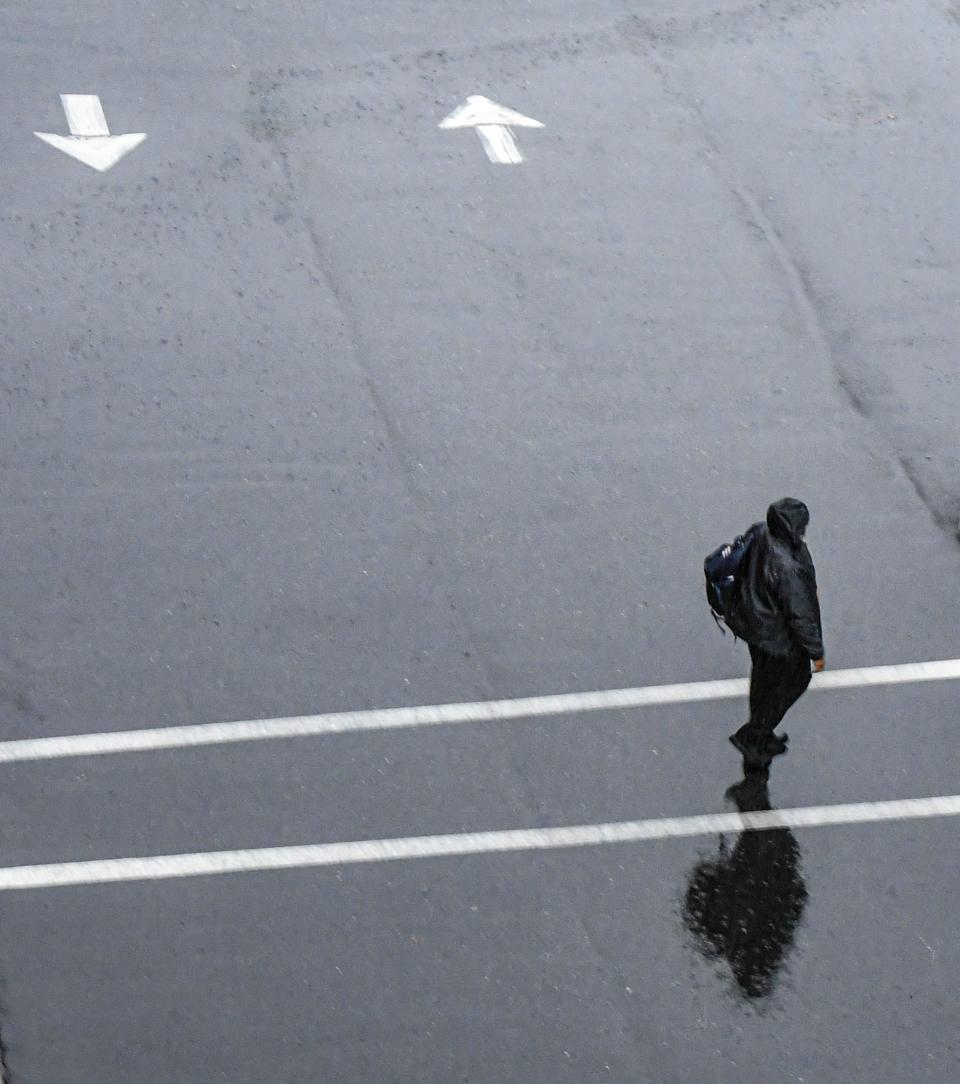 A man walks to work in downtown as rain falls on Anderson, S.C. Tuesday, January 9, 2024.