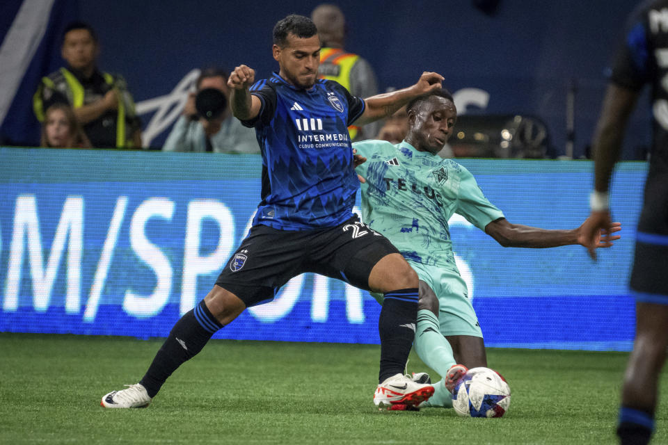 San Jose Earthquakes' Miguel Trauco (21) and Vancouver Whitecaps' Richie Laryea, right, battle for the ball during first-half MLS soccer match action in Vancouver, British Columbia, Sunday, Aug. 20, 2023. (Ethan Cairns/The Canadian Press via AP)