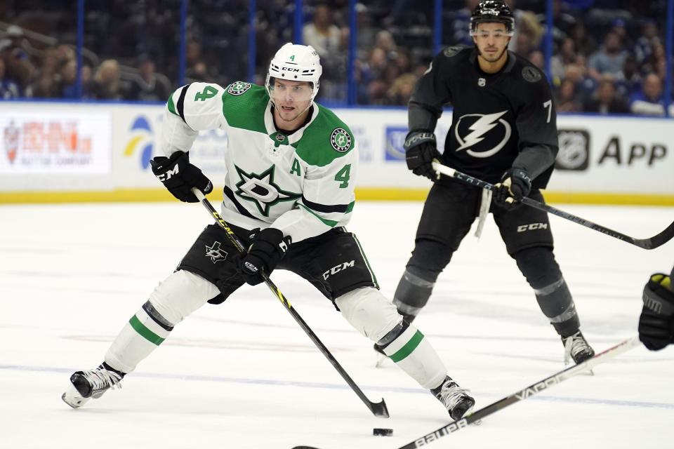 Dallas Stars defenseman Miro Heiskanen (4) carries the puck past Tampa Bay Lightning right wing Mathieu Joseph (7) during the third period of an NHL hockey game Saturday, Jan. 15, 2022, in Tampa, Fla. (AP Photo/Chris O'Meara)