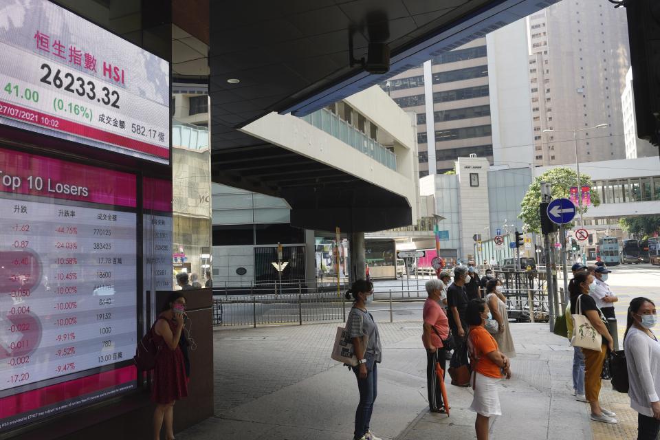 People stand in front of a bank's electronic board showing the Hong Kong share index at Hong Kong Stock Exchange in Hong Kong Tuesday, July 27, 2021. Asian stock markets were mostly higher Tuesday as investors looked ahead to a Federal Reserve report for an update on when U.S. stimulus might start winding down. (AP Photo/Vincent Yu)