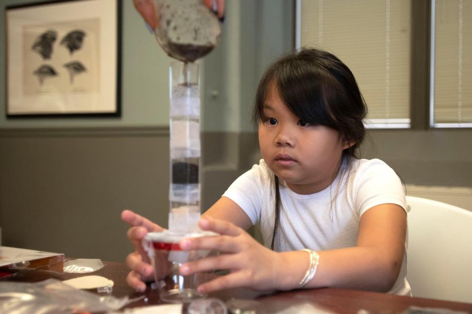 Girls Code the World summer camp student Aimi looks at her water filter experiment as the instructor pours dirty water at the Academy of Natural Sciences in Philadelphia on Thursday, June 30, 2022.