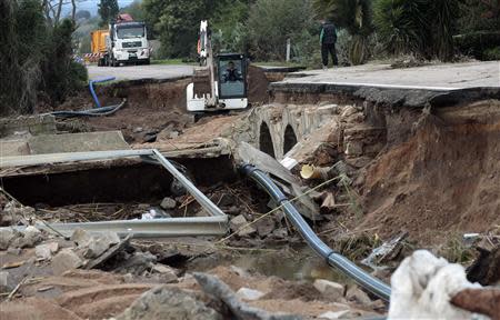 Labourers work on a damaged road following an extreme rainfall near Olbia on Sardinia island November 20, 2013. REUTERS/Tony Gentile