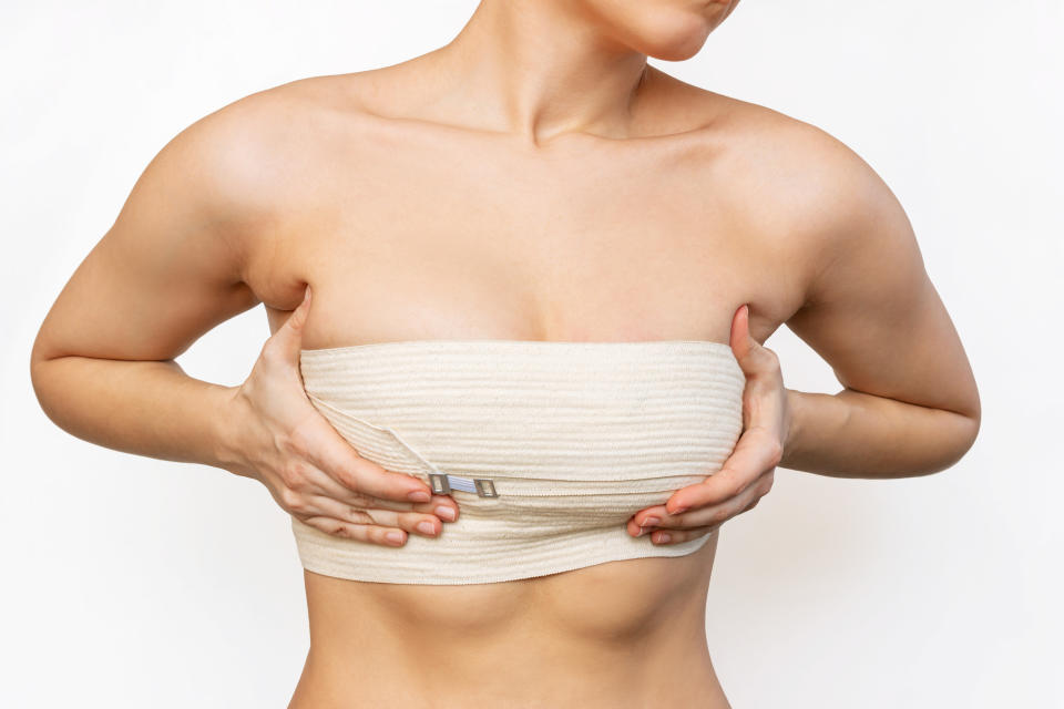 A woman gripping her breasts that have an elastic band around them