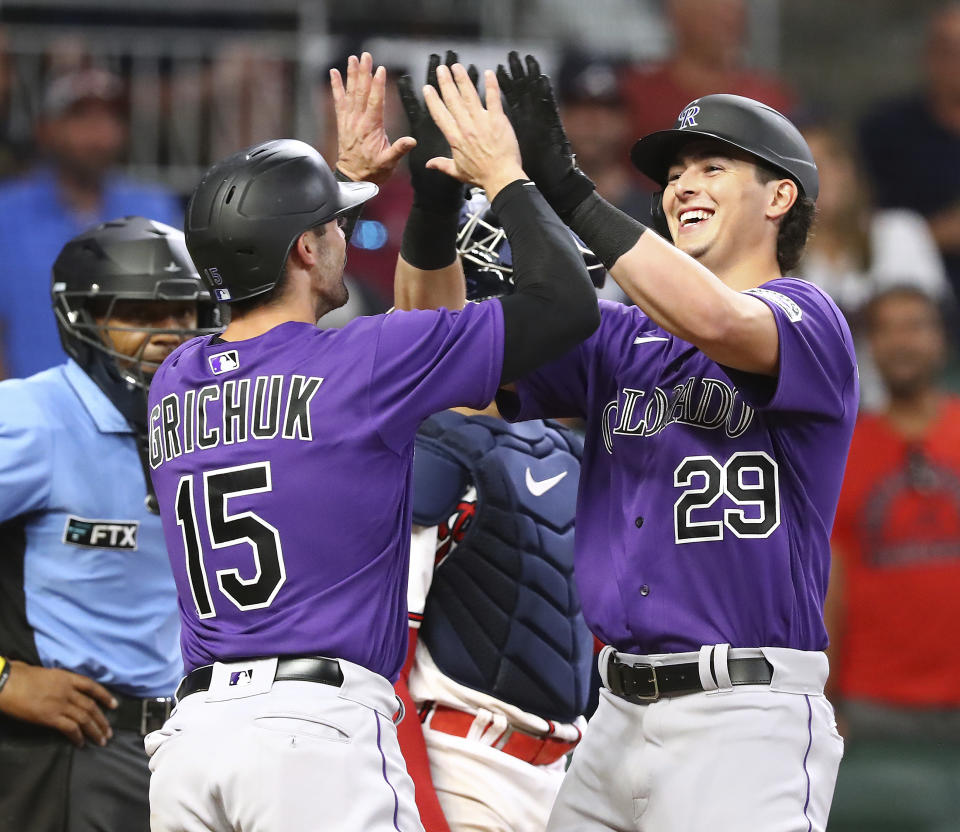 Colorado Rockies Michael Toglia (29) gets a double high five from Randal Grichuk (15) at home after hitting a two-RBI home run to break up a shutout by the Atlanta Braves closer Kenley Jansen during the ninth inning of a baseball game Wednesday, Aug. 31, 2022 in Atlanta. (Curtis Compton/Atlanta Journal-Constitution via AP)