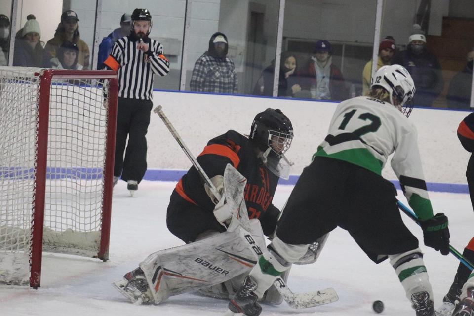 Gardner High goaltender Mark Quinn, left, makes a save against Greenfield's Trevor Kuchieski (12) during a preliminary round game of the Division 4 state tournament, Wednesday, in Greenfield.