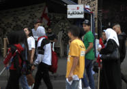 In this Friday, Nov. 8, 2019 photo, anti-government protesters pass by an Arabic placard that reads, "Not for sectarianism," in downtown Beirut, Lebanon. Lebanon’s protests have brought out people from across the country’s spectrum of faiths and communities trying to throw out the entire ruling elite. (AP Photo/Hussein Malla)