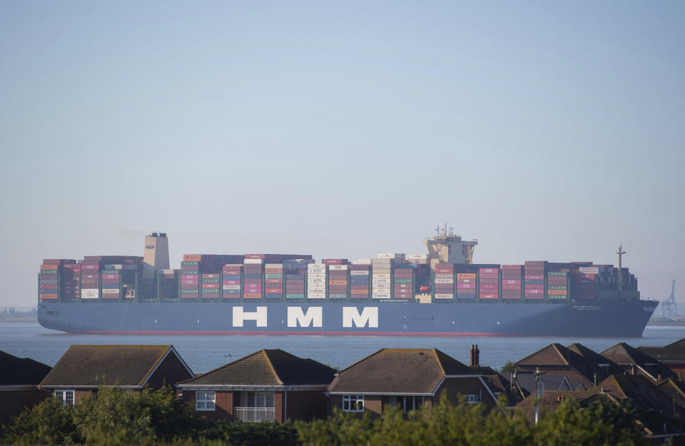 HMM Algeciras, the world's largest container ship, towers over houses as it passes Canvey Island in Essex.