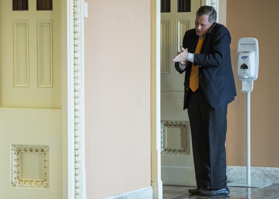 Sen. Richard Burr (R-N.C.) sanitizes his hands while talking on his cell phone outside the Mansfield Room in the Capitol on Jan. 8, 2015.