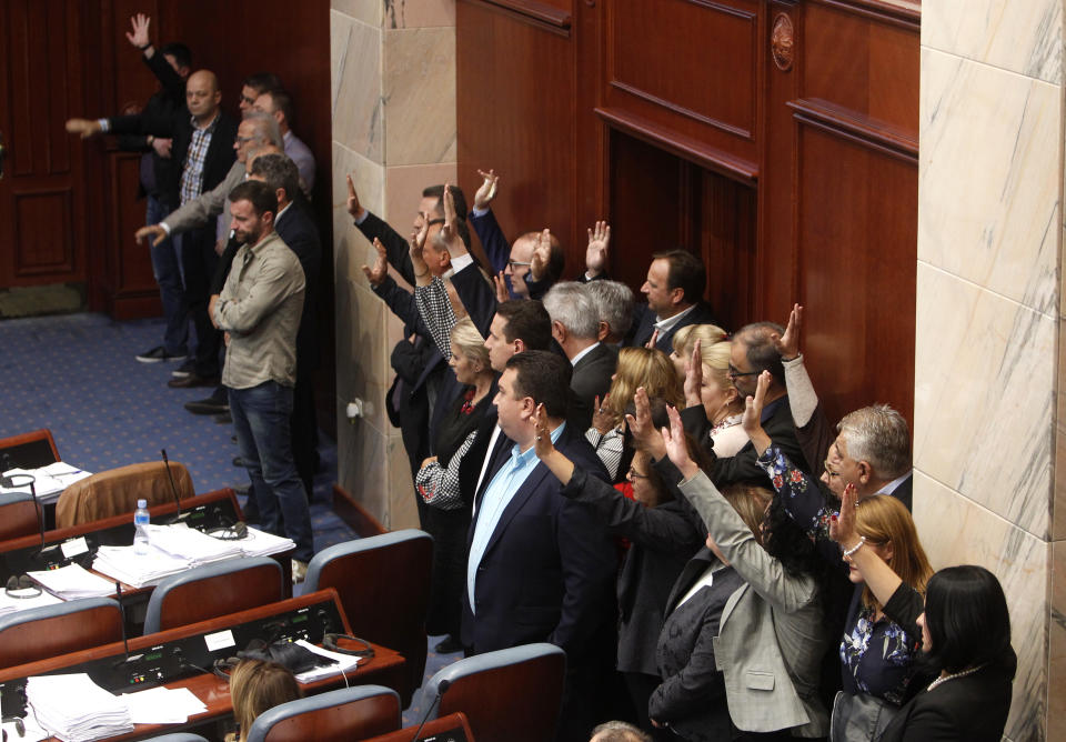 Lawmakers of the opposition VMRO-DPMNE stand on the right and react during the voting on proposal on a motion for constitutional revision during a session of the Macedonian Parliament in the capital Skopje, Friday, Oct. 19, 2018. Lawmakers in Macedonia on Friday backed the landmark proposal to amend the constitution, allowing the country to change its name and join NATO. (AP Photo/Boris Grdanoski)