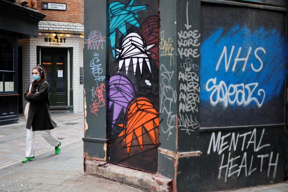 A woman wearing a face mask as a precautionary measure against COVID-19, walks past closed shops in the City of London, on January 15, 2021, during the third coronavirus lockdown. - Britain's economy slumped 2.6 percent in November on coronavirus restrictions, official data showed January 15, 2021, stoking fears that the current virus lockdown could spark a double-dip recession. (Photo by Tolga Akmen / AFP) (Photo by TOLGA AKMEN/AFP via Getty Images)