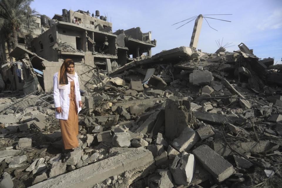 A Palestinian woman walks past the destruction from the Israeli bombardment