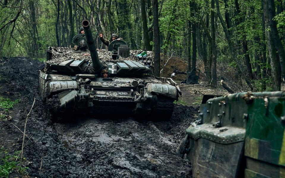 Ukrainian soldiers wave atop a passing tank on the frontline in Bakhmut, Donetsk region - LIBKOS/AP