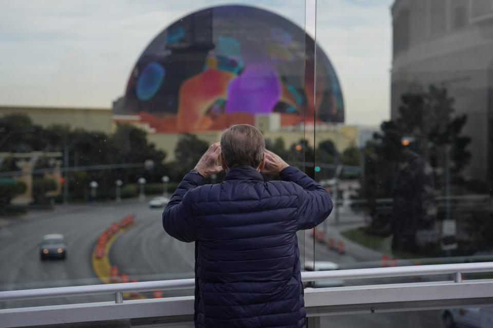 A person stops to take a picture of the Sphere on a pedestrian bridge along the Las Vegas Strip, Wednesday, Jan. 17, 2024, in Las Vegas. Stopping or standing is prohibited on Las Vegas Strip pedestrian bridges after a new ordinance took effect Tuesday, Jan. 17, 2024. (AP Photo/John Locher)