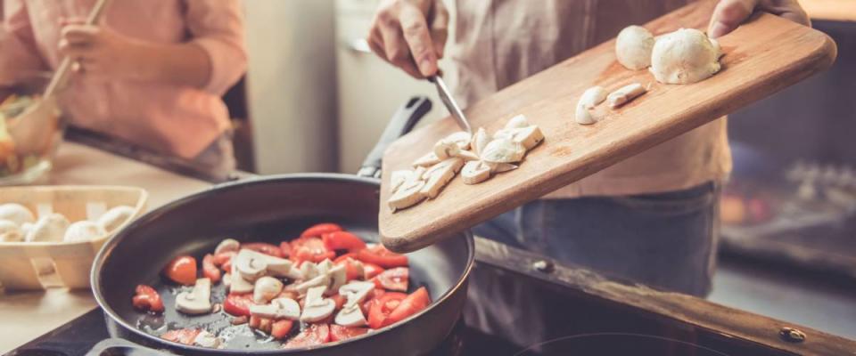 Cropped image of cute little girl and her beautiful parents cooking together in kitchen at home