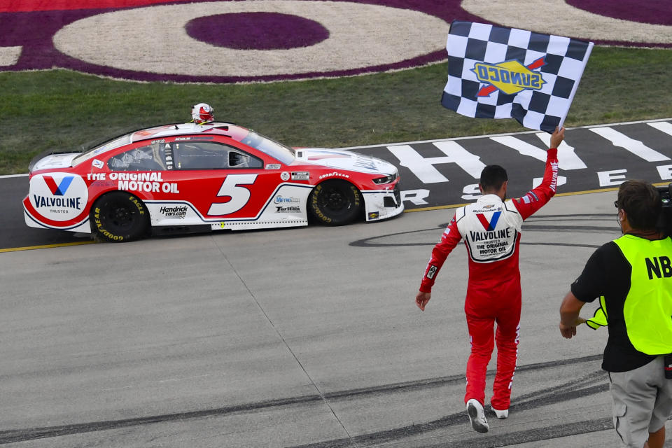 Kyle Larson walks back to his car with the checkered flag after winning a NASCAR Cup Series auto race Sunday, June 20, 2021, in Lebanon, Tenn. (AP Photo/John Amis)