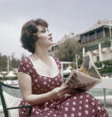 ARCHIVO - La actriz Gina Lollobrigida le una revista sentada junto a una piscina durante su estancia en un hotel de Beverly Hills en Los Angeles, California el 10 de mayo de 1959. La leyenda del cine italiano Gina Lollobrigida, que alcanzó el estrellato cinematográfico internacional durante la década de 1950 y fue apodada “la mujer más bella del mundo” por el título de una de sus películas, murió en Roma el lunes 16 de enero de 2023, dijo su agente. Tenía 95 años (Foto AP, archivo)