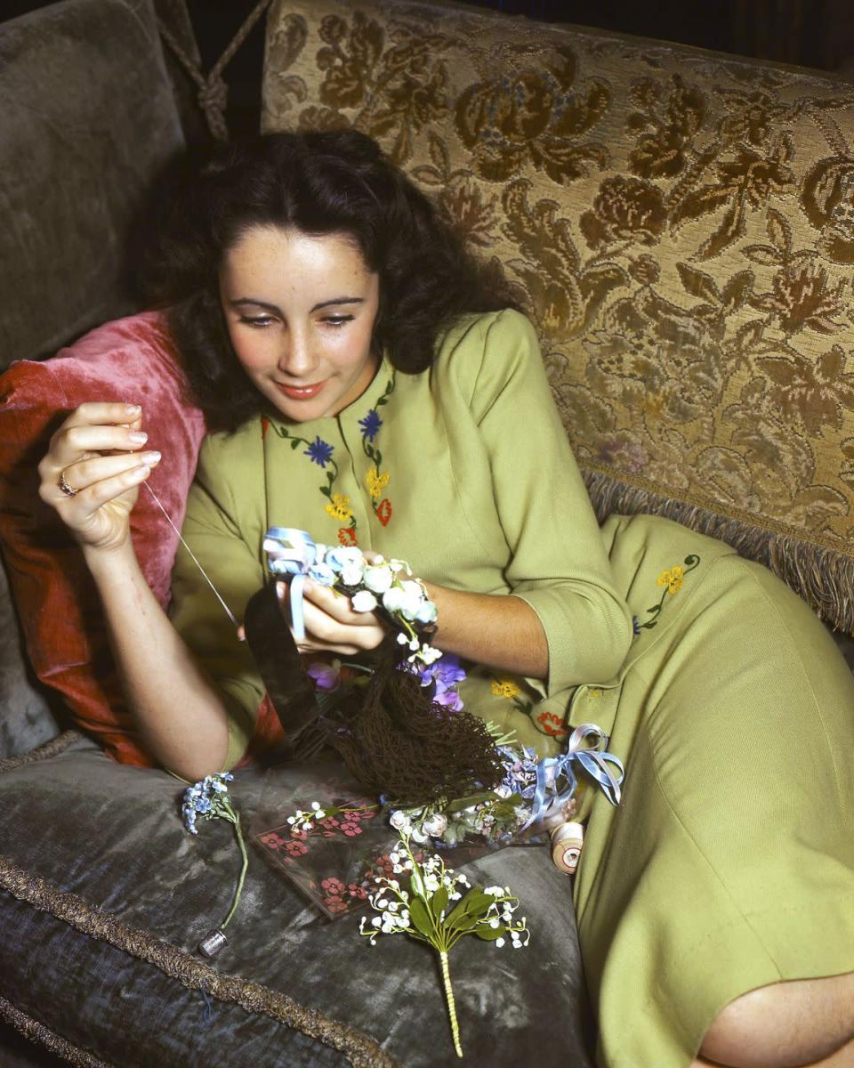 <p>The actress is seen sewing preserved flowers into a hair piece in 1950. </p>