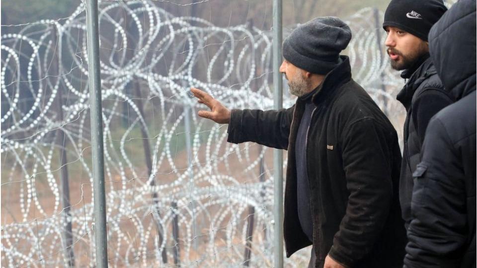 Migrantes junto a una valla de alambre de púas en la frontera entre Bielorrusia y Polonia