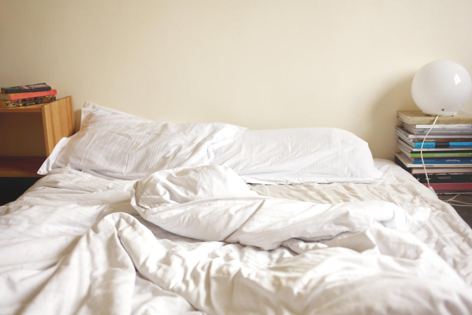 Unmade bed in the morning showing clean white bedding and pillows.