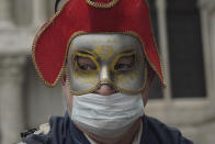 A Russian tourist dons both a carnival mask and a protective face mask as he visits St. Mark's square Venice, Italy, Tuesday, Feb. 25, 2020. Italy has been scrambling to check the spread of Europe's first major outbreak of the new viral disease amid rapidly rising numbers of infections and calling off the popular Venice Carnival and closing tourist attractions. (AP Photo/Renata Brito)