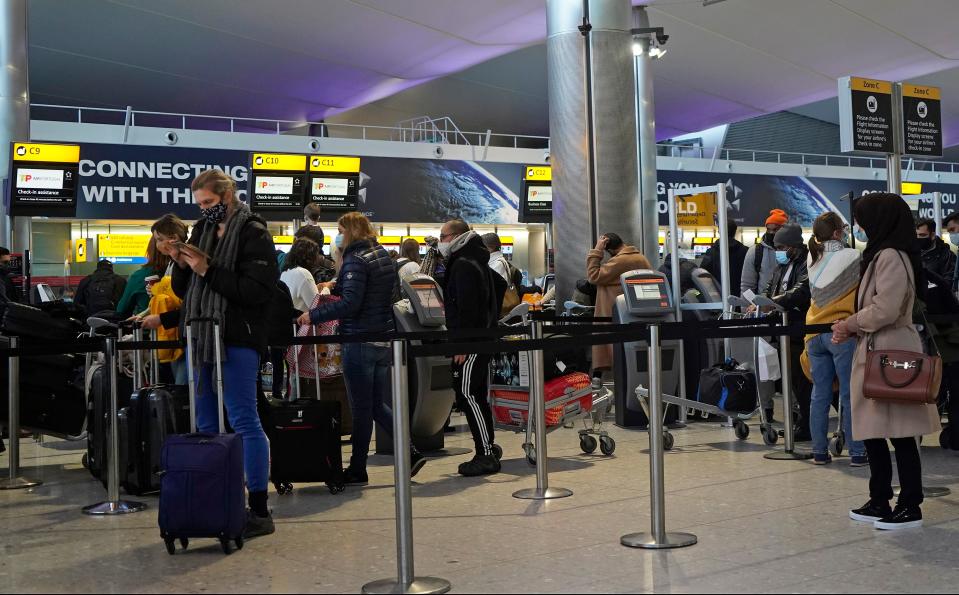 Customers wearing face covers queue at a TAP Air Portugal check-in desk in the departures hall at Terminal 2 of Heathrow Airport in west London on December 21, 2020, as a string of countries around the world banned travellers arriving from the UK, due to the rapid spread of a new, more-infectious coronavirus strain. - Prime Minister Boris Johnson was to chair a crisis meeting Monday as a growing number of countries blocked flights from Britain over a new highly infectious coronavirus strain the UK said was "out of control". (Photo by Niklas HALLE'N / AFP) (Photo by NIKLAS HALLE'N/AFP via Getty Images)