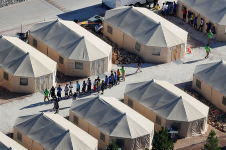 Immigrant children now housed in a tent encampment under the new "zero tolerance" policy by the Trump administration are shown walking in single file at the facility near the Mexican border in Tornillo, Texas, U.S. June 19, 2018. REUTERS/Mike Blake