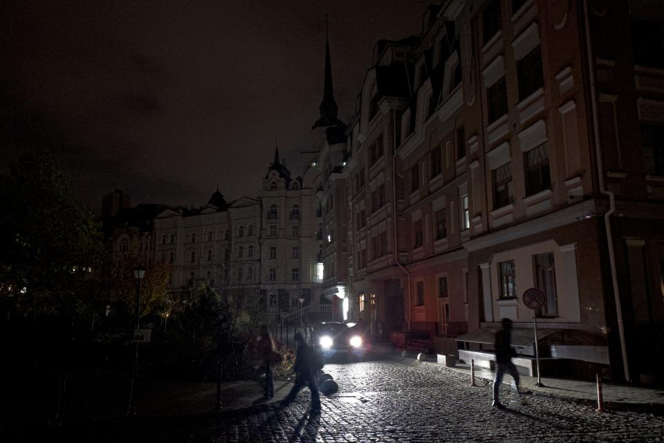 A car passes as city lighting turned off at twilight in Kyiv downtown, Ukraine, Monday, Oct. 31, 2022. Rolling blackouts are increasing across Ukraine as the government rushes to stabilize the energy grid and repair the system ahead of winter.