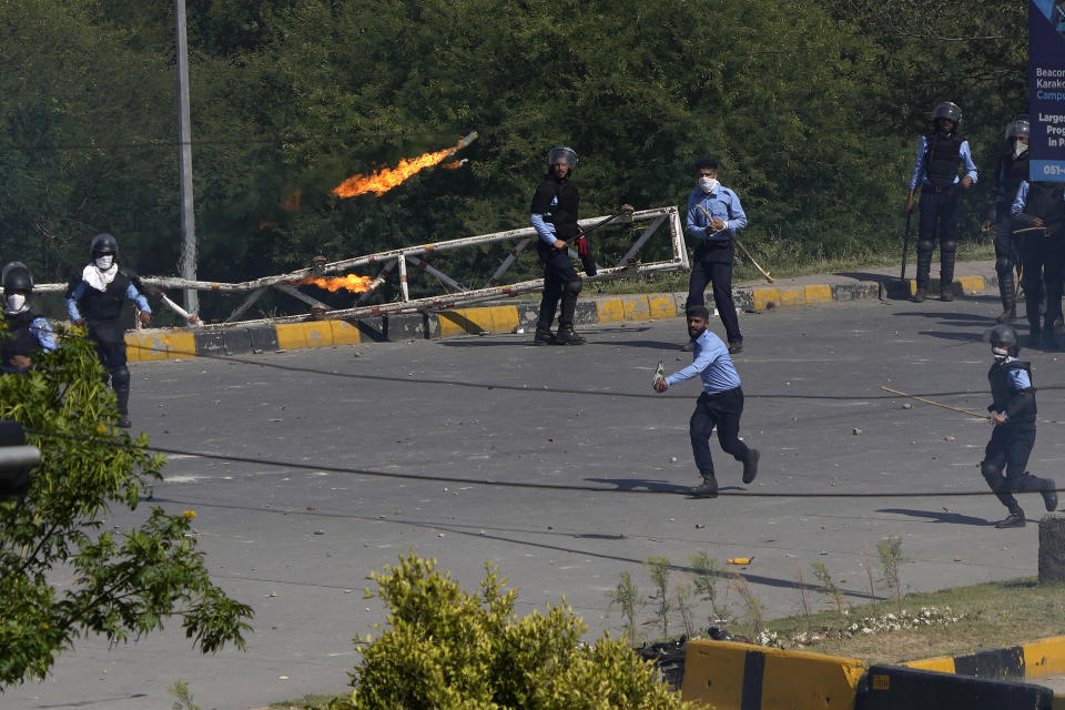 A supporter of Pakistan's former Prime Minister Imran Khan throws a petrol bomb toward police officers during clashes, in Islamabad, Pakistan, Wednesday, May 10, 2023. A court has ruled that former Pakistani Prime Minister Imran Khan can be held for questioning for eight days. The decision Wednesday comes a day after the country’s popular opposition leader was dragged from a courtroom and arrested. His detention set off clashes between his supporters and police Tuesday. (AP Photo/Anjum Naveed)