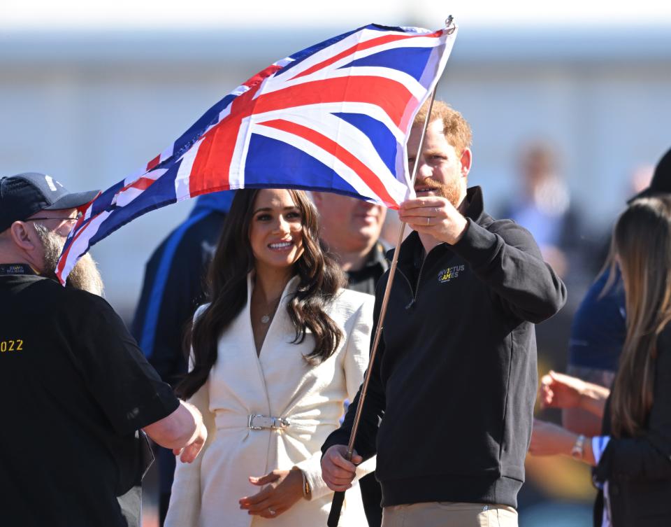 prince harry and meghan markle attend the invictus games and hold up a british flag