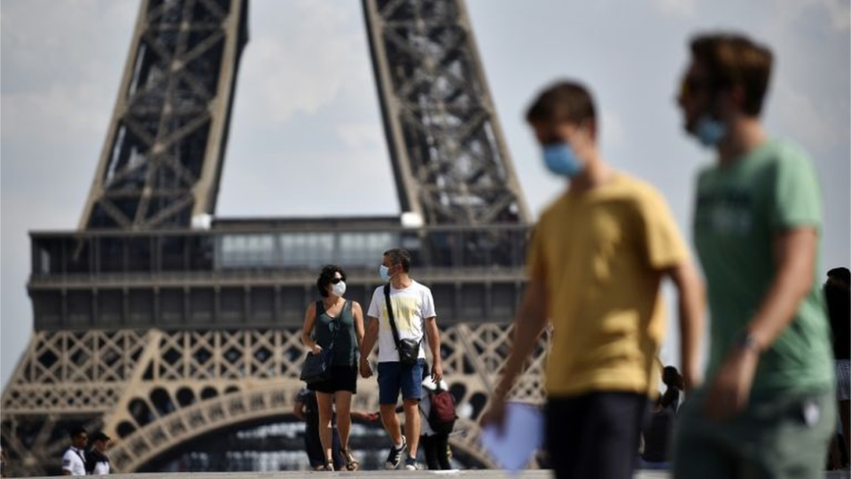 Personas con mascarilla frente a la Torre Eiffel en Paris