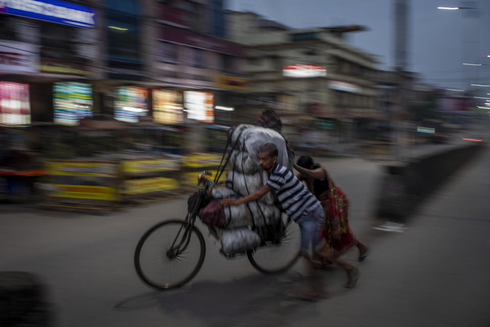 A couple pushes a bicycle, loaded with sacks of coal, to sell it to traders, early in the morning through a street in Dhanbad, an eastern Indian city in Jharkhand state, Sept. 24, 2021. No country will see energy needs grow faster in coming decades than India, and even under the most optimistic projections part of that demand will have to be met with dirty coal power — a key source of heat-trapping carbon emissions. (AP Photo/Altaf Qadri)