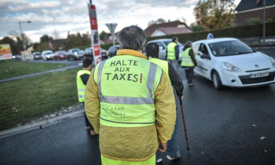 Man in yellow waistcoat reading 'stop the taxes' in French