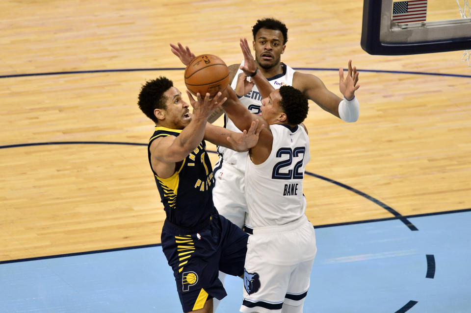 Indiana Pacers guard Malcolm Brogdon (7) shoots against Memphis Grizzlies guard Desmond Bane (22) and center Xavier Tillman (2)in the second half of an NBA basketball game Sunday, April 11, 2021, in Memphis, Tenn. (AP Photo/Brandon Dill)