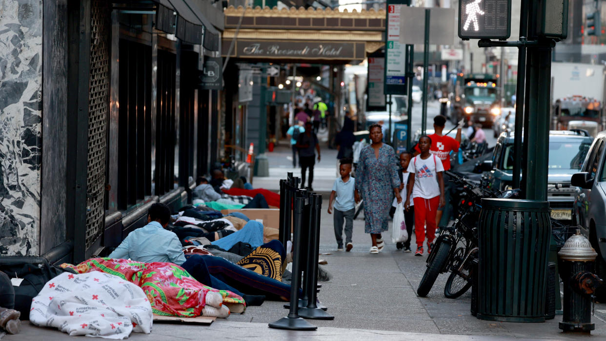 A dozen migrants are seen sleeping on the sidewalk outside the Roosevelt Hotel.