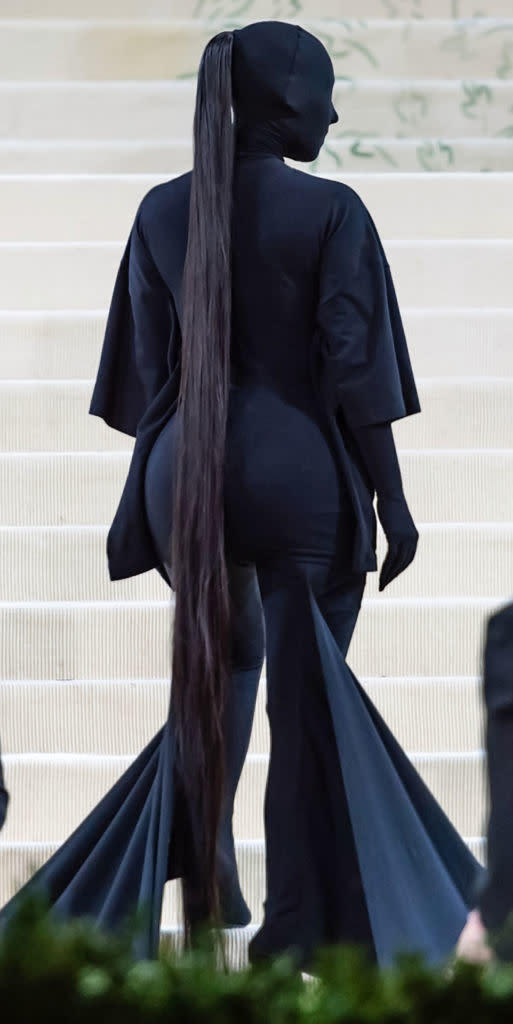 Kim in a full-coverage outfit with a long ponytail on stairs