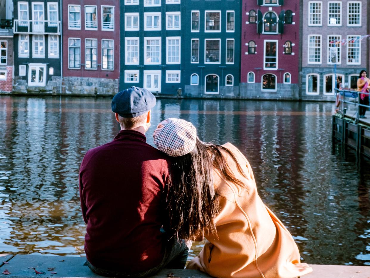 Amsterdam Damrak during sunset, happy couple man and woman on a summer evening at the canals