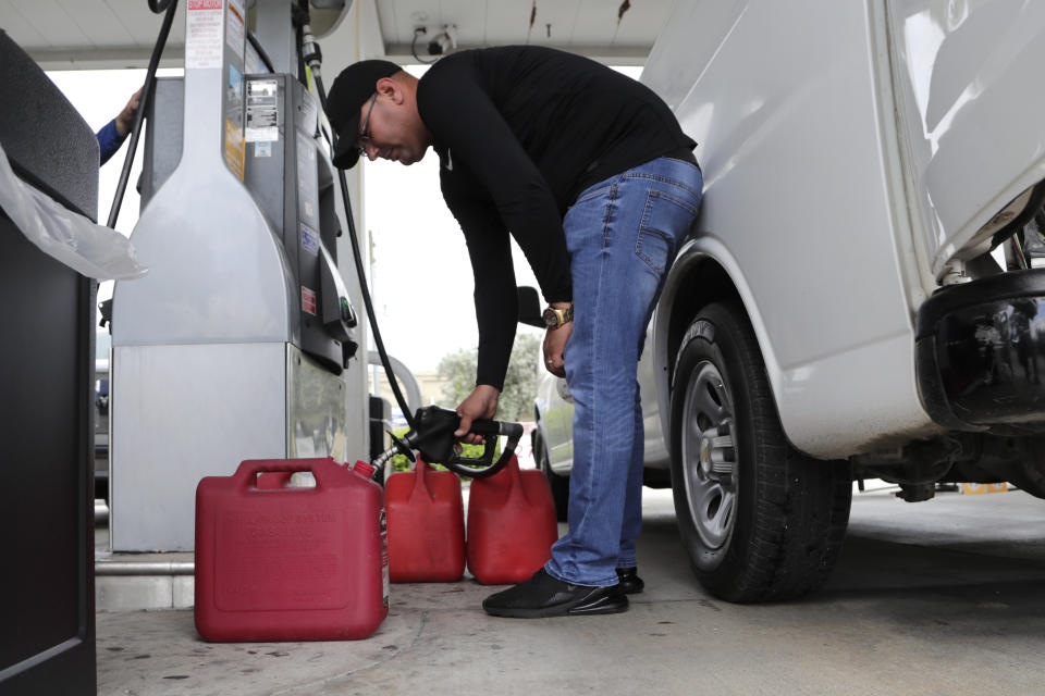 Arian Britto fills containers with gasoline at BJ's Wholesale Club in preparation for Hurricane Dorian, Thursday, Aug. 29, 2019, in Hialeah, Fla. Hurricane Dorian is heading towards Florida for a possible direct hit on the state over Labor Day. (AP Photo/Lynne Sladky)