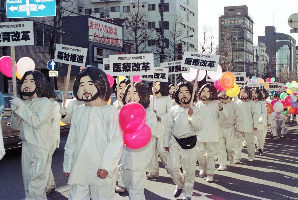 Members of Japanese doomsday cult Aum Shinrikyo wear masks of their guru Shoko Asahara while parading through Tokyo on January 27, 1990