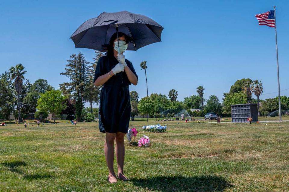Tracy Nguyen, uses an umbrella to shield the sun while standing alone during the funeral for her boyfriend Dung Tan Nguyen at Sacramento Memorial Lawn on Wednesday, May 6, 2020, during the coronavirus outbreak.