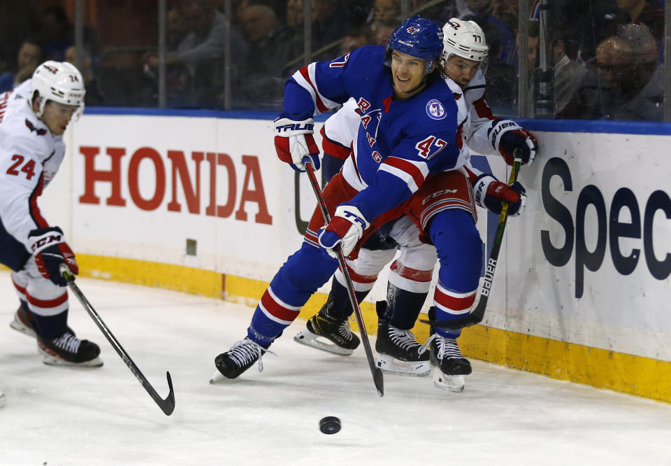 New York Rangers' Morgan Barron (47) clears the puck from behind the net while being defended by Washington Capitals' Connor McMichael (24) and T.J. Oshie (77) during the first period of an NHL hockey game Thursday, Feb. 24, 2022, in New York. (AP Photo/John Munson)