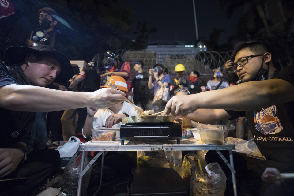 Pro-democracy protesters share a meal outside Police headquarters during a rally in Bangkok, Thailand, Wednesday, Nov. 18, 2020. Police in Thailand's capital braced for possible trouble Wednesday, a day after a protest outside Parliament by pro-democracy demonstrators was marred by violence that left dozens of people injured. (AP Photo/Wason Wanichakorn)