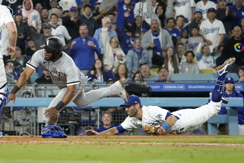 Los Angeles Dodgers third baseman Chris Taylor, right, falls after tagging out Chicago White Sox's Elvis Andrus after Andrus was caught between third and home during the seventh inning of a baseball game Thursday, June 15, 2023, in Los Angeles. (AP Photo/Mark J. Terrill)