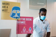 In this Monday, July 6, 2020 photograph, a front desk employee wearing a mask due to the coronavirus pandemic works on his computer at the Rove City Centre Hotel in Dubai, United Arab Emirates, Monday, July 6, 2020. Dubai reopened for tourists Tuesday amid the coronavirus pandemic, hoping to reinvigorate a vital industry for this city-state before its crucial winter tourist season. (AP Photo/Jon Gambrell)