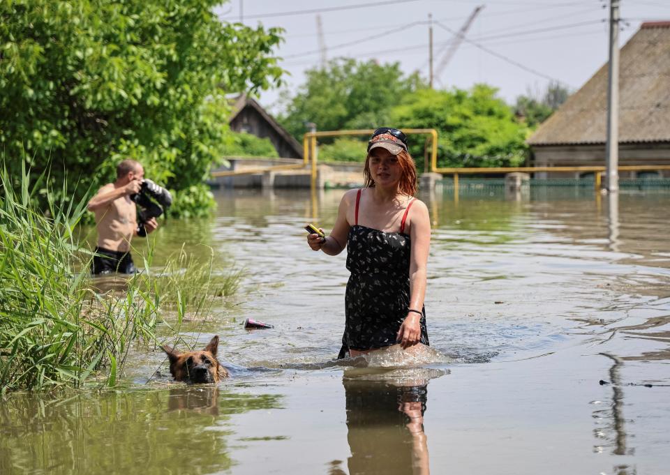 Local residents walk in a flooded street during an evacuation from a flooded area after the Nova Kakhovka dam breached (REUTERS)